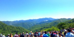 Natură verde și oameni zâmbitori înconjurând munți.