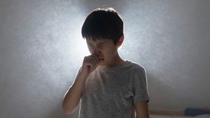 Copil tușind în aer poluat din interior.